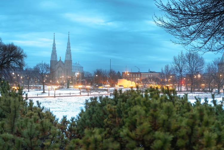 Three women in an office setting collaborate around a laptop, smiling and engaged in discussion.